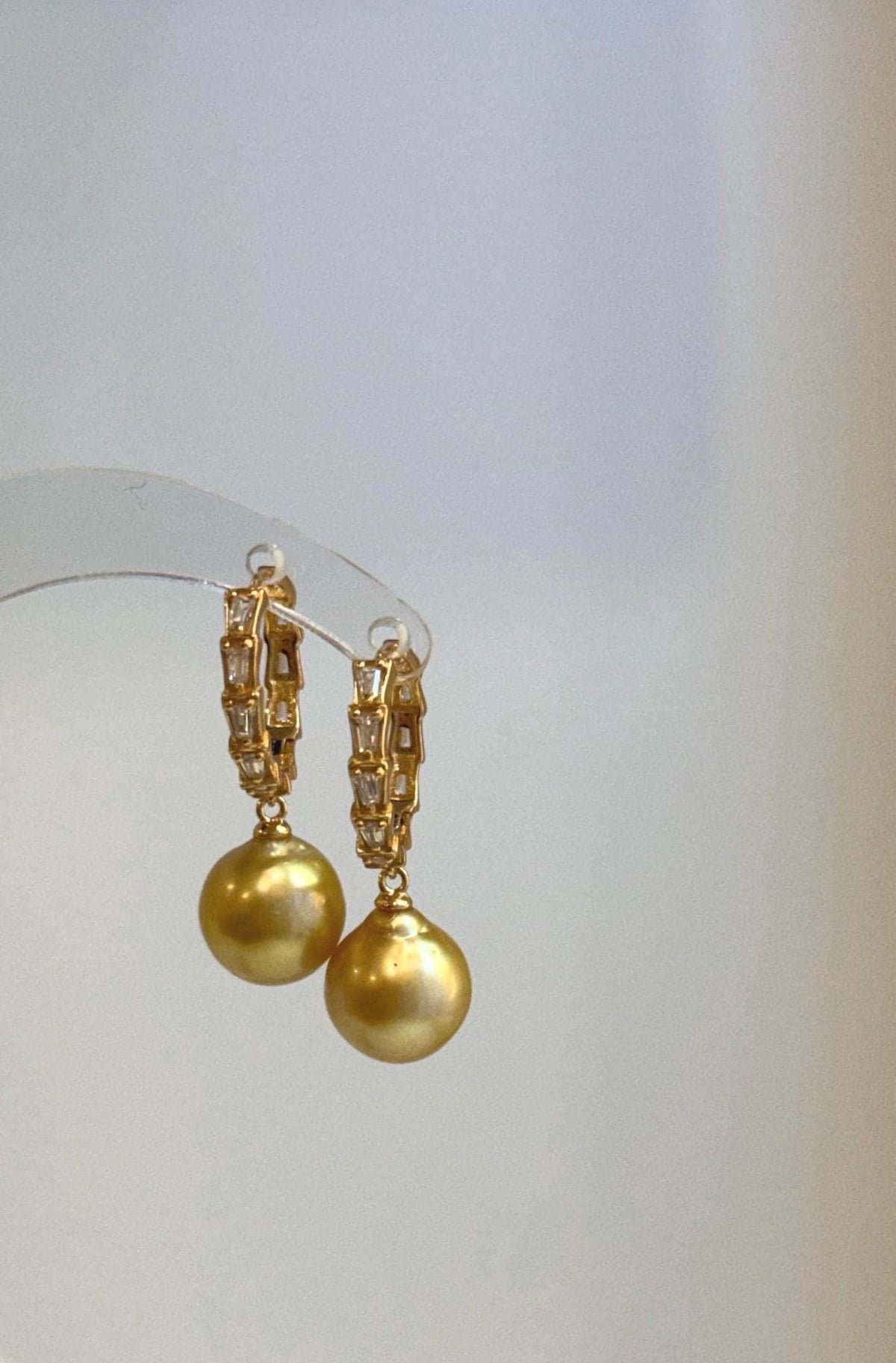 Elegant hoop earrings featuring rich golden pearls and shimmering crystal accents.