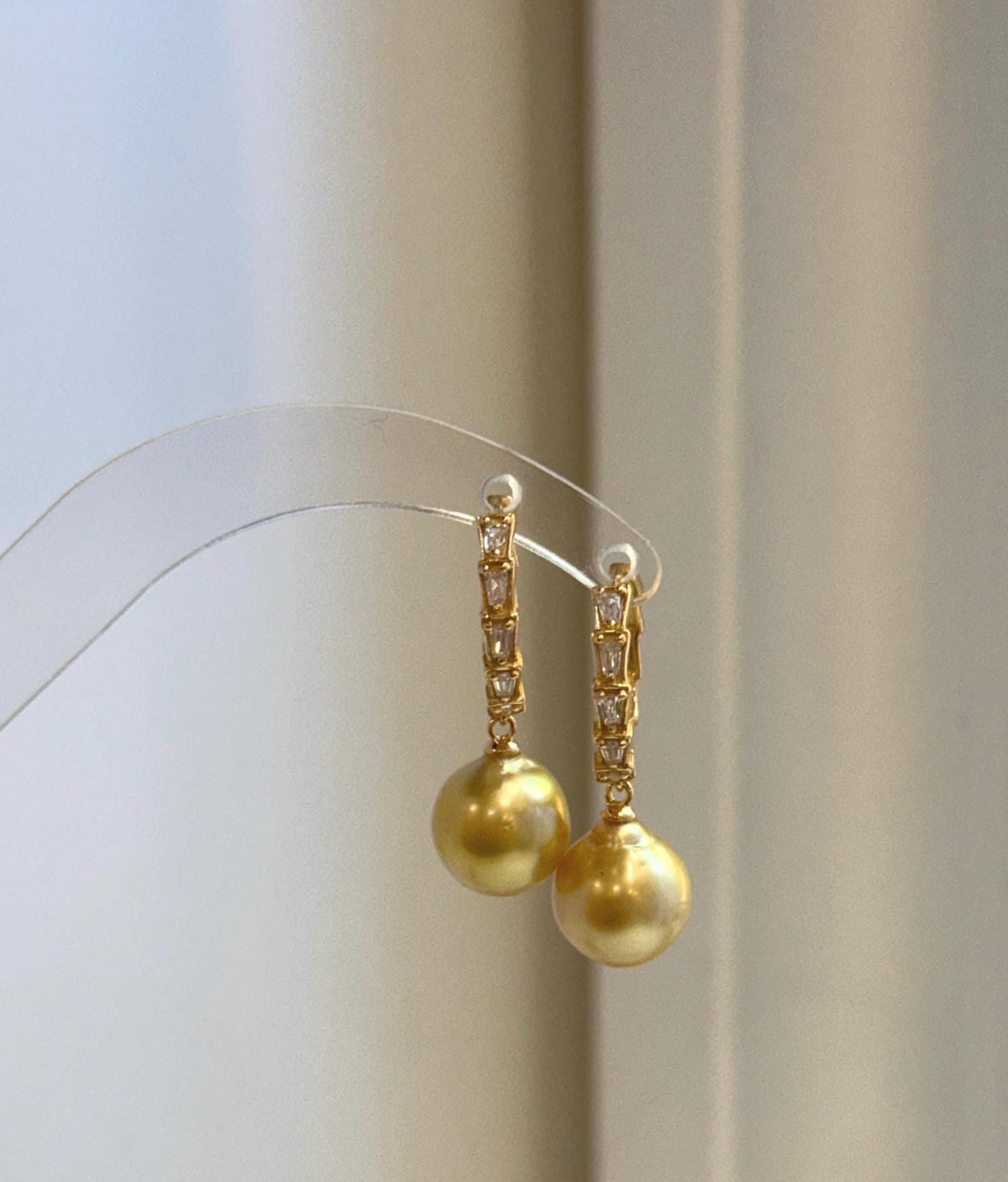 Gold-tone hoops frame luminous South Sea pearls for a classic evening look.