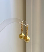 Gold-tone hoops frame luminous South Sea pearls for a classic evening look.