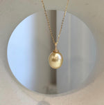 South Sea pearl drop pendant featuring a warm golden color and reflective surface.