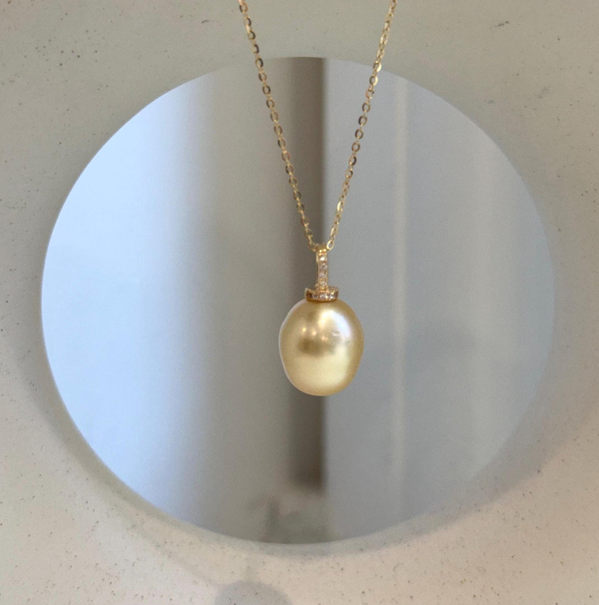 South Sea pearl drop pendant featuring a warm golden color and reflective surface.