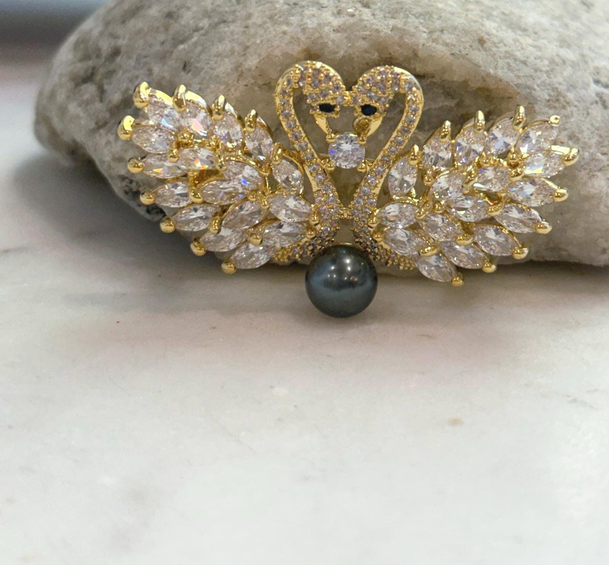 Front view of a two-in-one swan jewelry piece that can be worn as a brooch or pendant, with a genuine Tahitian pearl as its focal point.