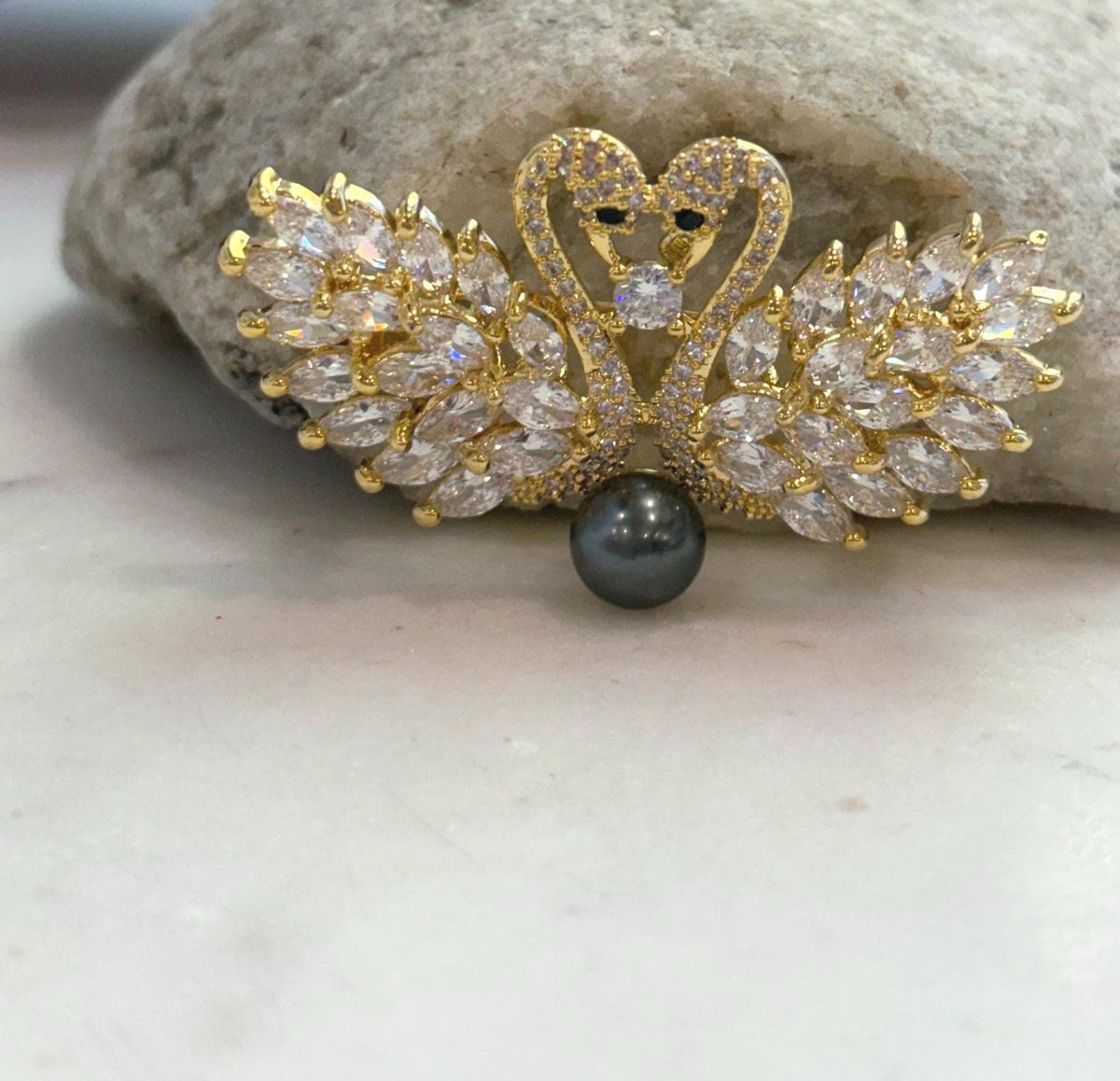 Elegant swan brooch with a genuine pearl as its focal point.