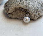 Australian white ocean pearl pendant resting beside its handwritten product label.