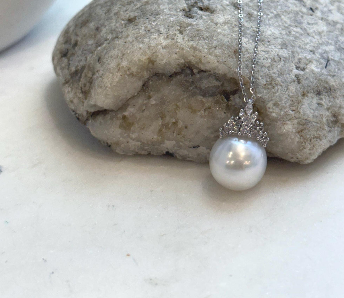 White pearl crown necklace framed by the circular opening of a cream display stand.