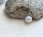 White ocean pearl pendant with subtle iridescent reflections and a sparkling crown cap.