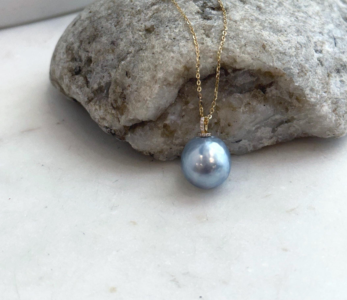 Mirror-luster silver blue saltwater pearl accented with moissanite in an 18K gold pendant.