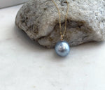Mirror-luster silver blue saltwater pearl accented with moissanite in an 18K gold pendant.