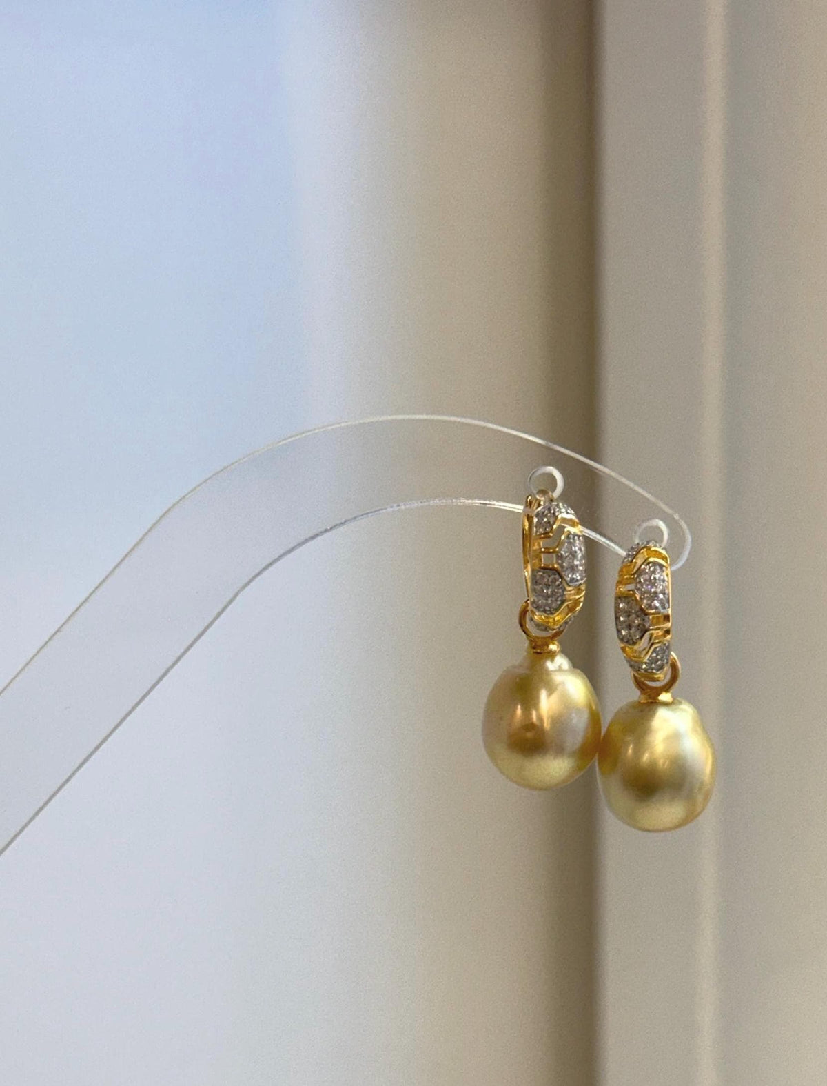 Detail of the crystal-accented gold-tone hoops above the golden pearls.
