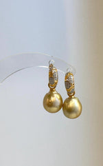 Side view showing the curved hoops and dangling golden pearl drops.