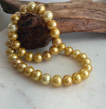 Statement necklace of luminous golden freshwater pearls arranged in a continuous strand.