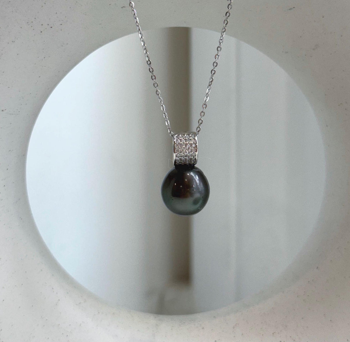 Reflective Tahitian pearl in a hunter green shade with sparkling crystal accents.
