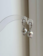 Oval carabiner-style S925 silver settings with suspended Akoya pearl drops.