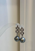 Side view of geometric silver earrings with luminous Tahitian pearl drops.