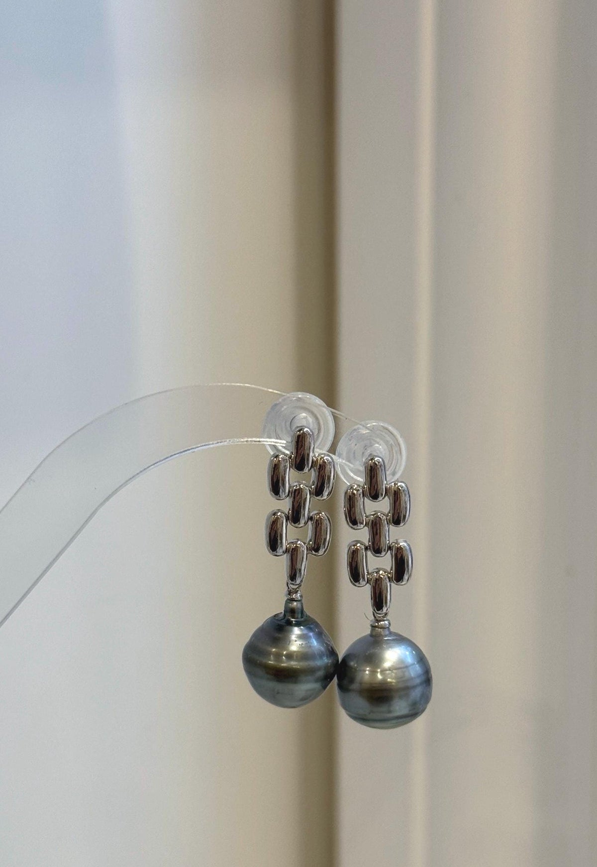 Side view of geometric silver earrings with luminous Tahitian pearl drops.