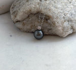 Tahitian pearl pendant featuring a reflective gray surface and sparkling crystal details.