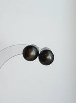 Genuine Tahitian pearl studs featuring platinum gray tones and a reflective surface.