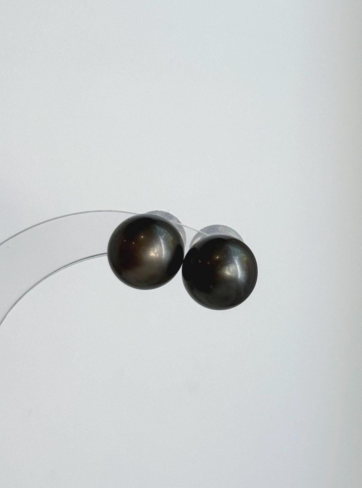 Genuine Tahitian pearl studs featuring platinum gray tones and a reflective surface.