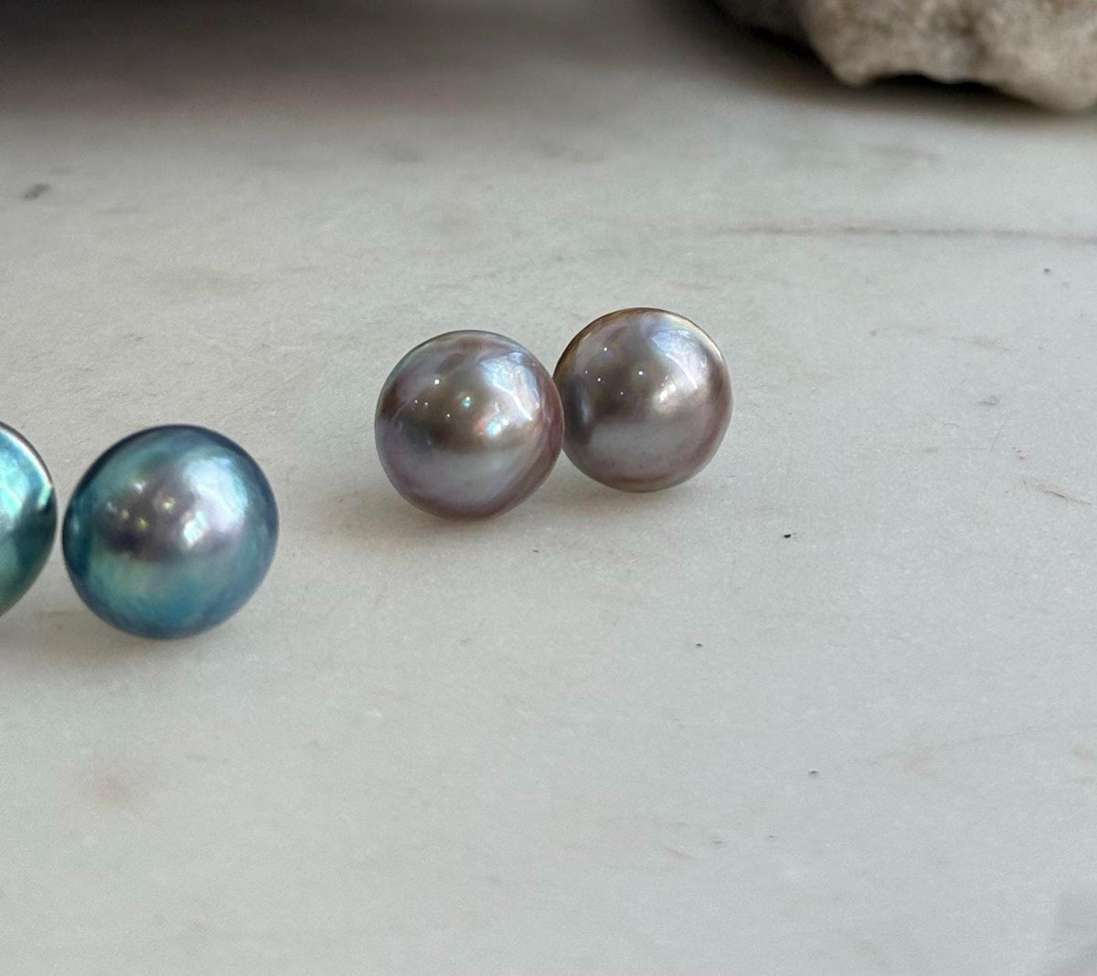 Round saltwater pearl earrings with mirror luster and shifting iridescent tones.