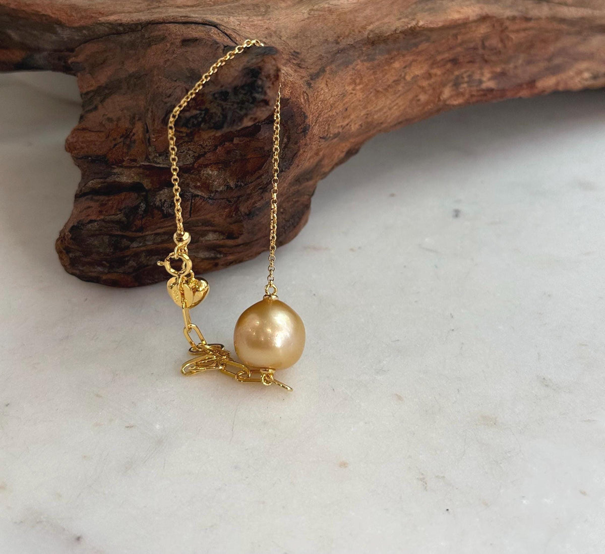Gold-tone heart charm on pearl bracelet.