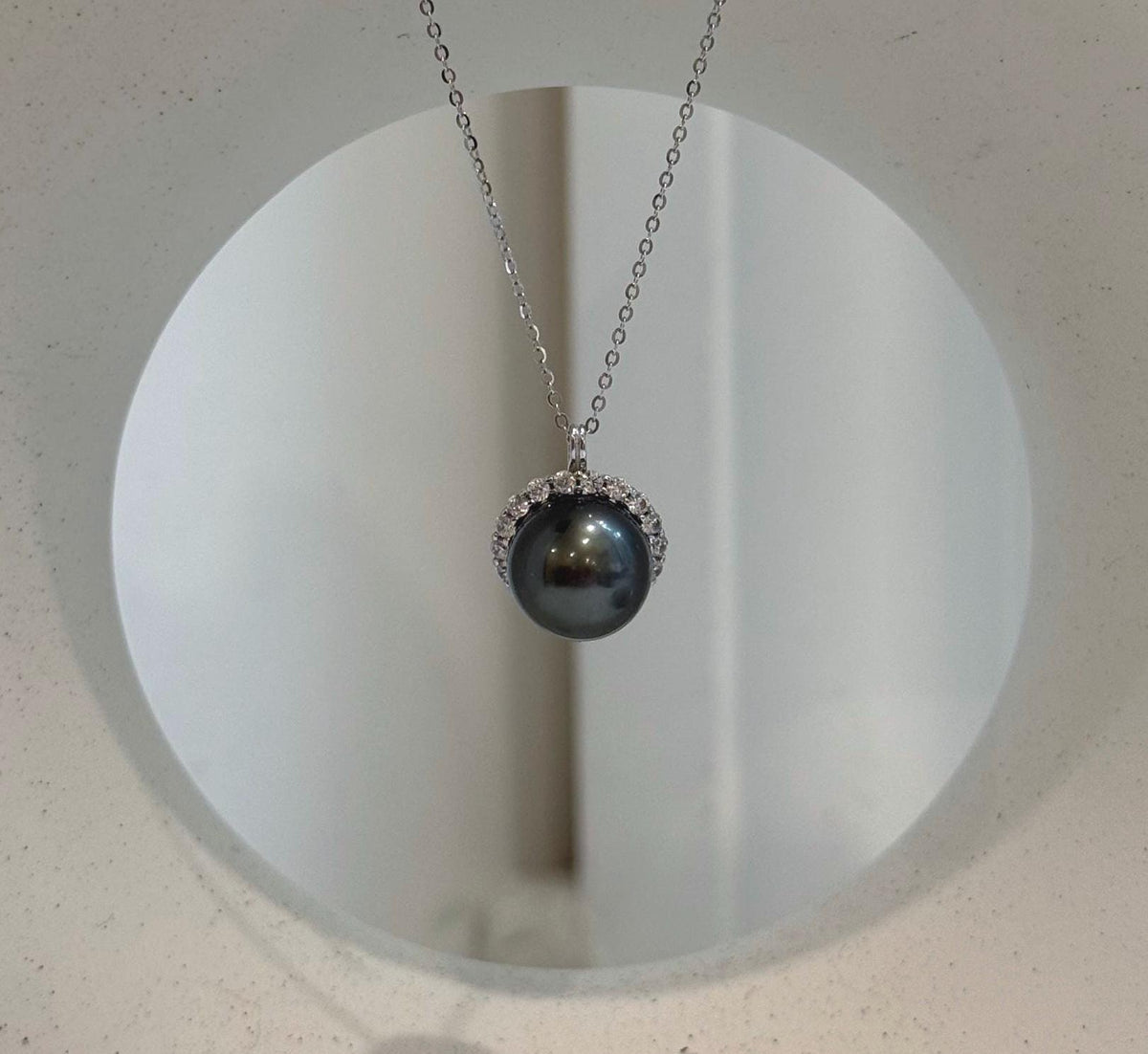 Piano black pearl necklace with a circular crystal setting.