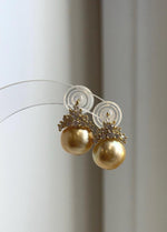 Golden pearl stud earrings with crystal-accented crown details.