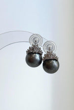 Crystal crown details above dark silver-gray pearls.