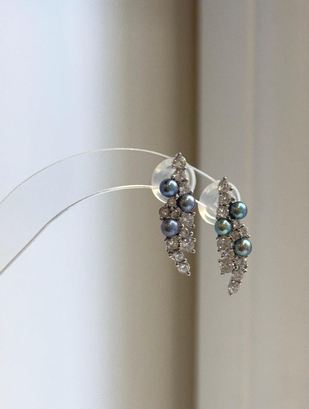 Iridescent freshwater pearls nestled among clear stones in a curved leaf design.