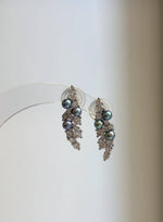 Dark freshwater pearls with teal and violet overtones in silver leaf settings.
