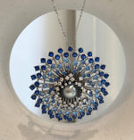 Round Tahitian pearl surrounded by radiating silver-tone branches and blue stones.