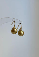 Golden pearl drop earrings with sculptural high heel silver hooks.