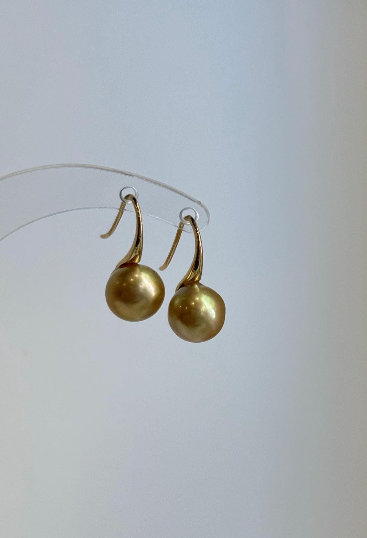 Golden pearl drop earrings with sculptural high heel silver hooks.