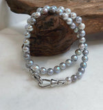 Saltwater pearls arranged in overlapping loops on a white background.