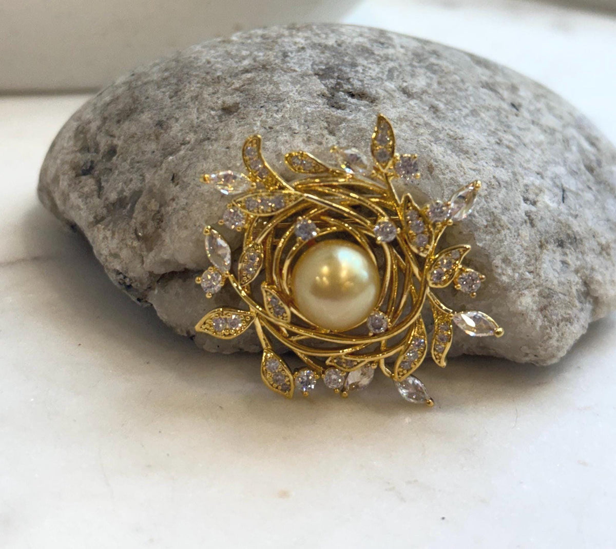 Pearl leaf wreath brooch displayed on a natural stone