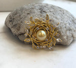 Pearl leaf wreath brooch displayed on a natural stone