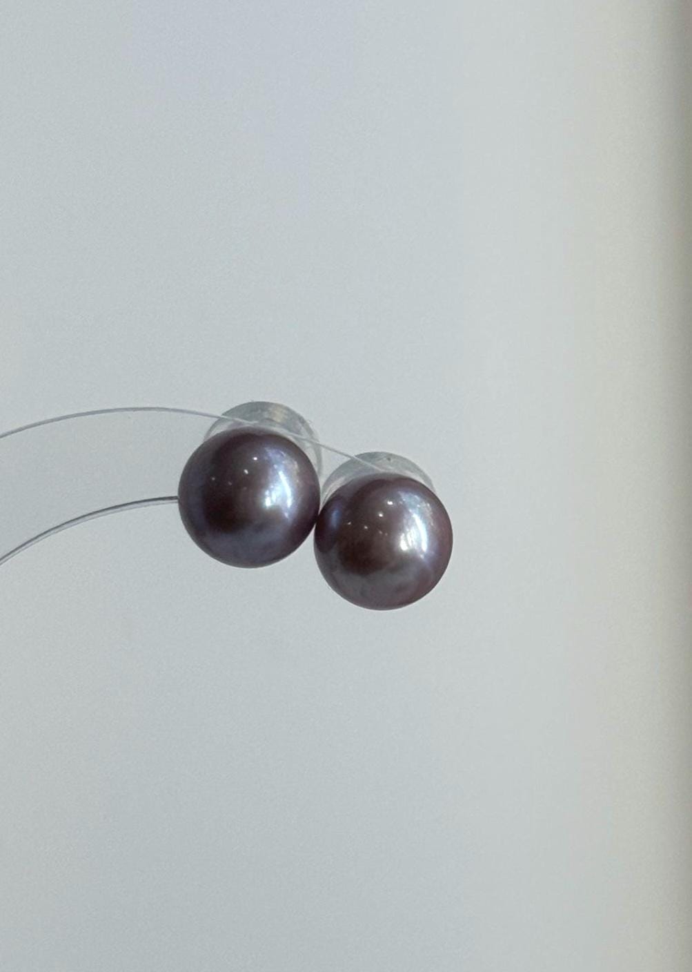 Lavender pearl necklace draped over a stone beside matching studs.