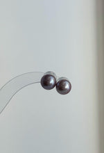 Matching freshwater pearl pendant and stud earrings on a pale surface.