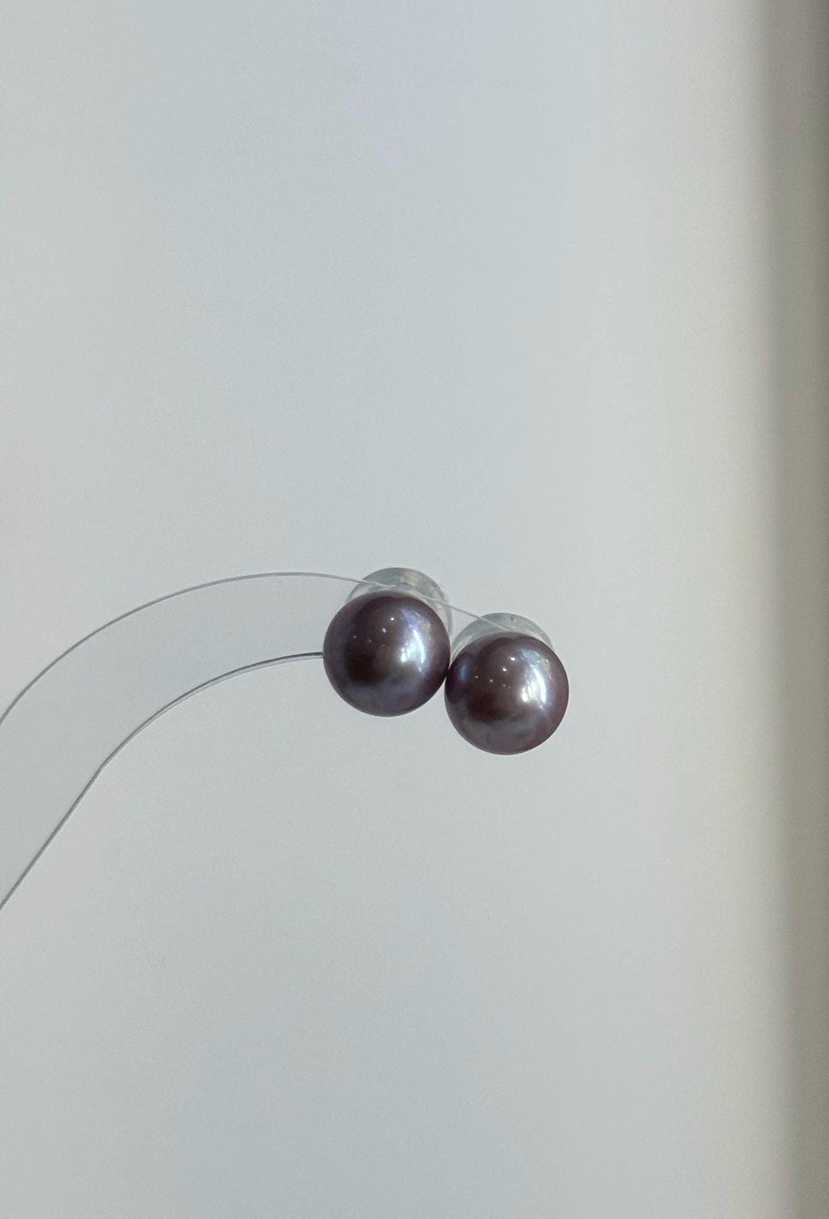 Matching freshwater pearl pendant and stud earrings on a pale surface.