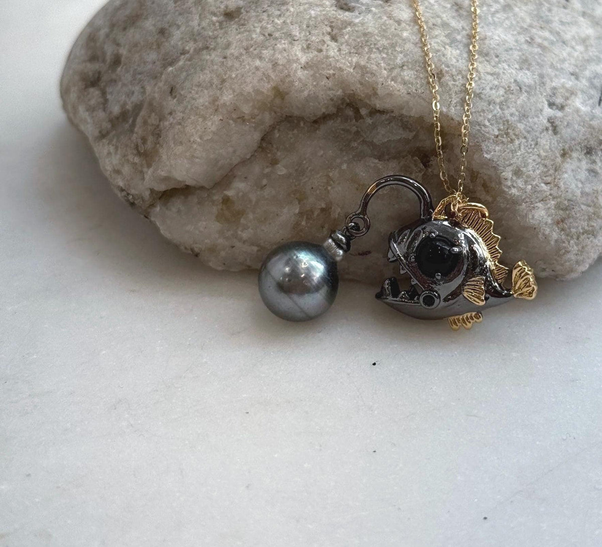 Tahitian pearl anglerfish necklace displayed on a white jewelry stand.
