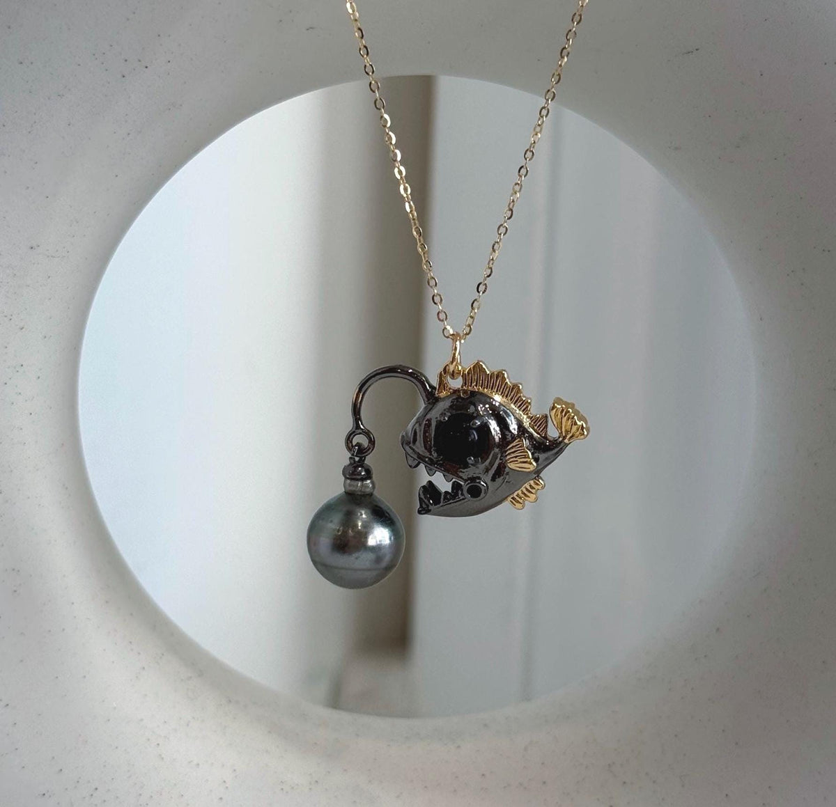 Ocean-inspired necklace featuring a Tahitian pearl and sculpted fish.