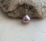 Rose pink pearl necklace displayed on a cream jewelry stand.