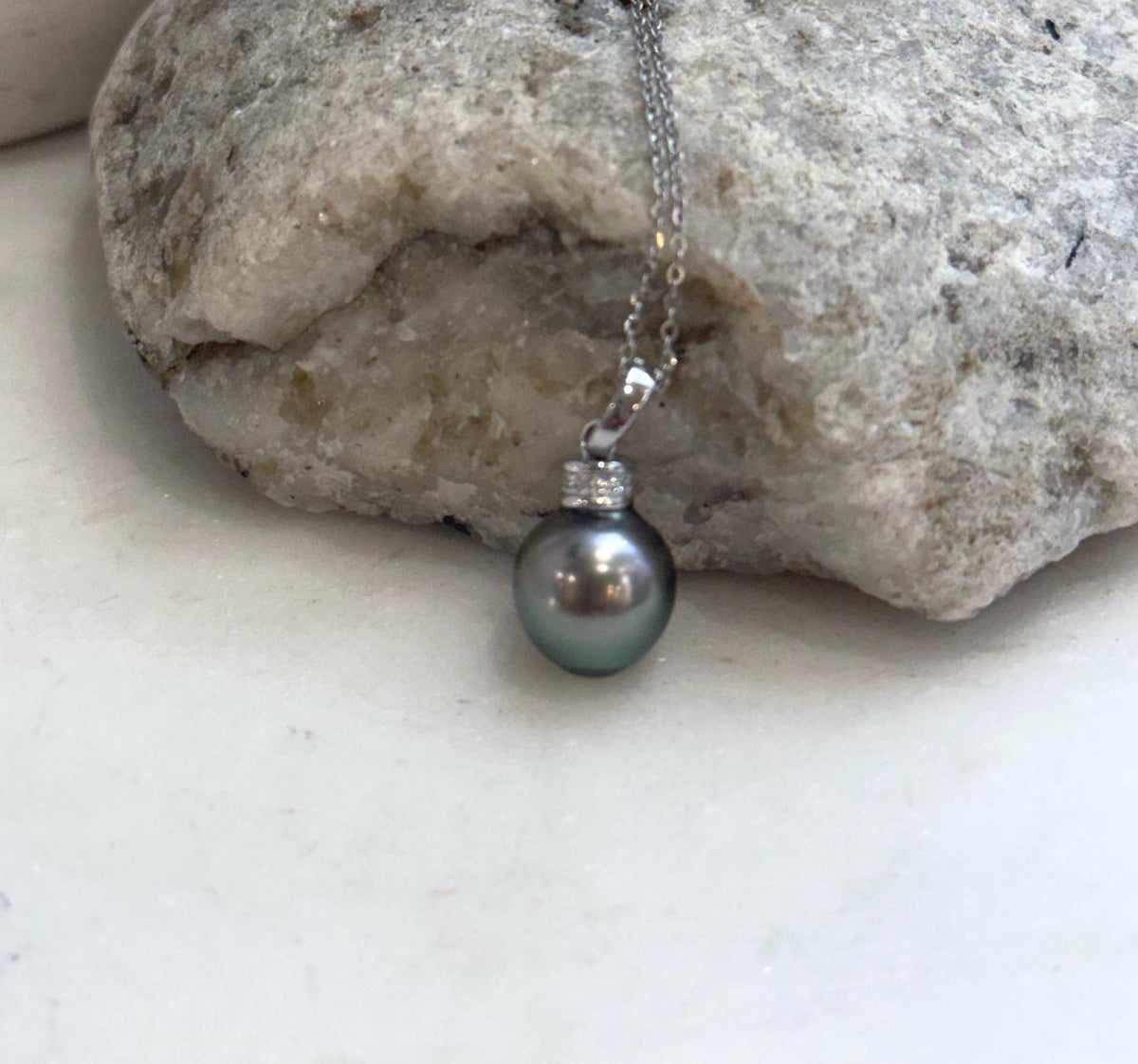 Genuine Tahitian pearl pendant necklace with a reflective green surface.