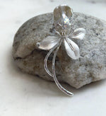 White pearl flower brooch with textured petals and sparkling accents.