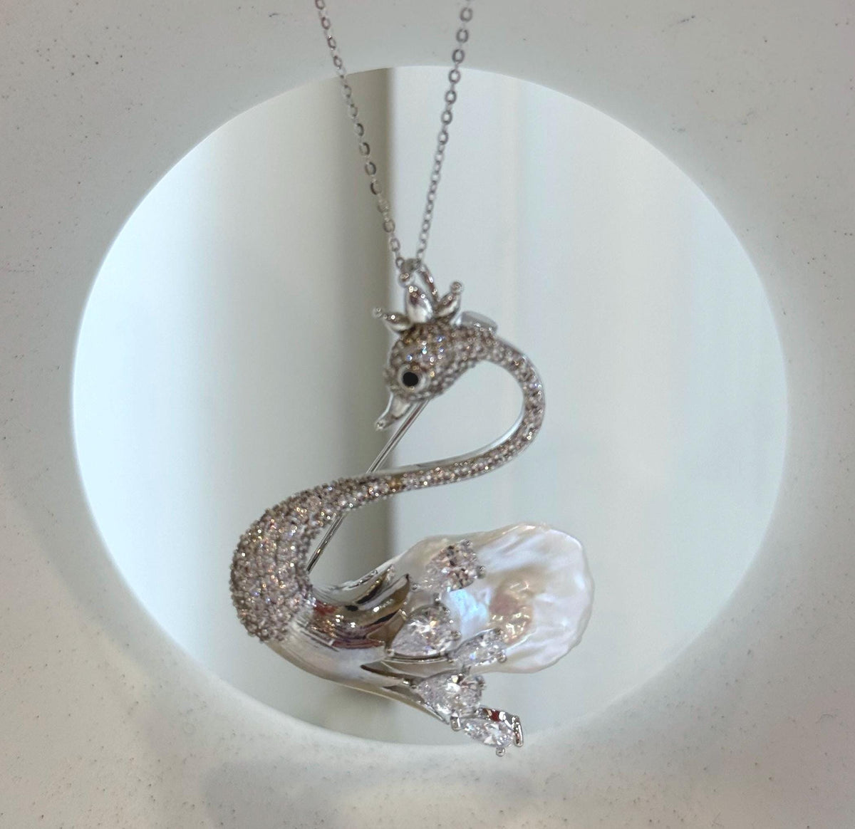 Silver-tone swan brooch featuring an iridescent white baroque pearl.