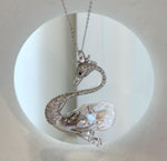 Silver-tone swan brooch featuring an iridescent white baroque pearl.