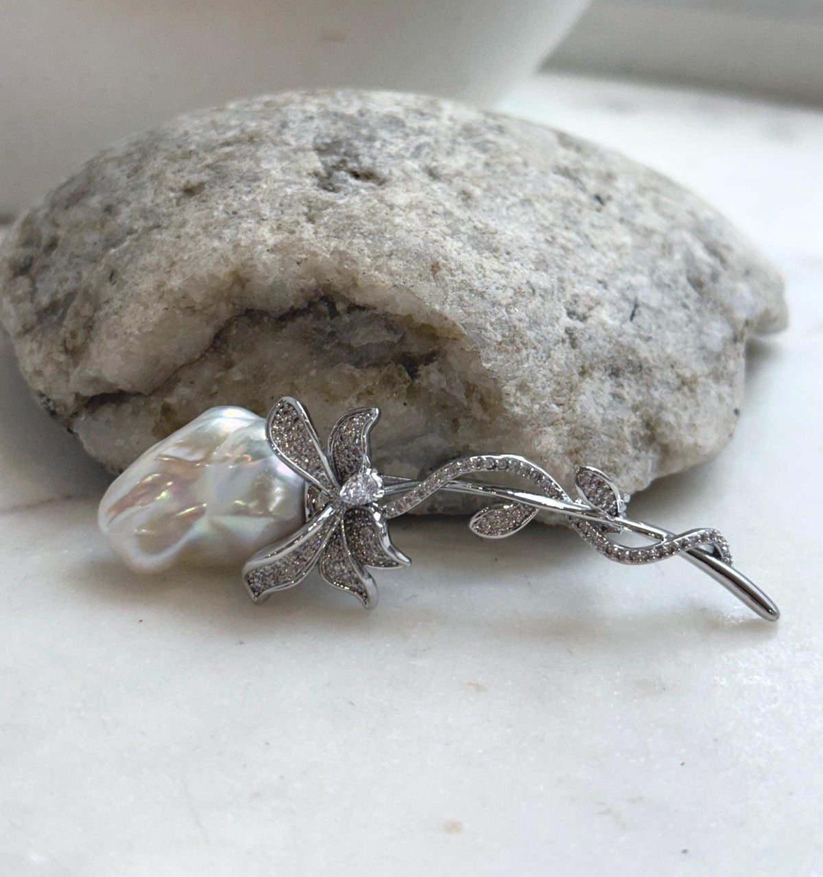 Iridescent white baroque pearl nestled in a delicate silver-tone vine design.