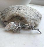 Iridescent white baroque pearl nestled in a delicate silver-tone vine design.