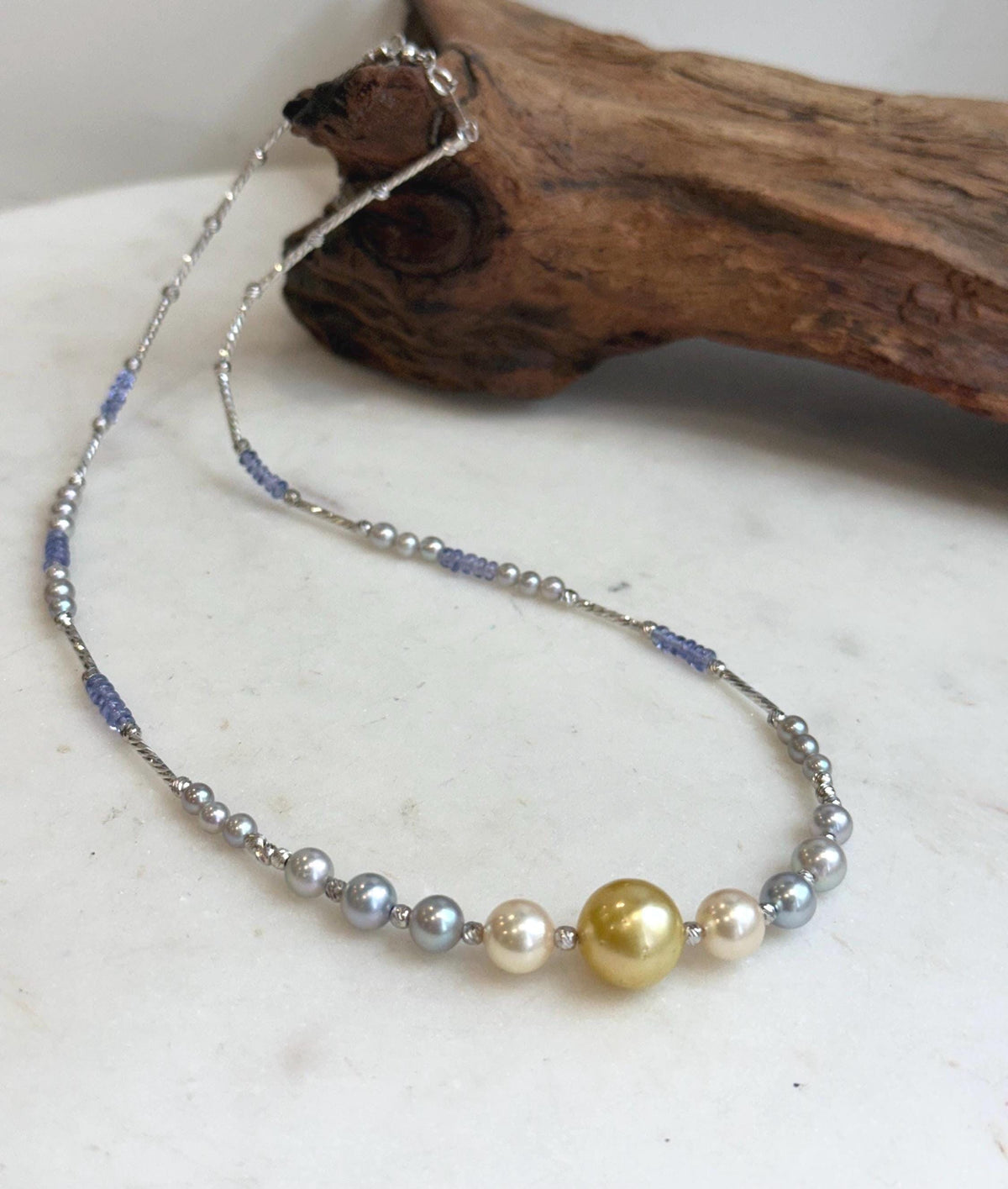 Golden center pearl framed by cream and silver-blue saltwater pearls.