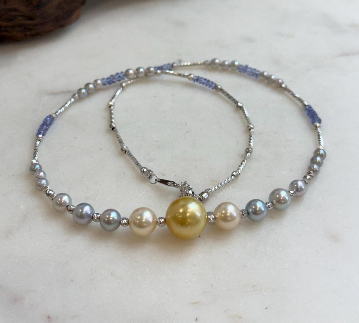 Saltwater pearl necklace with a golden center pearl and blue tanzanite beads.