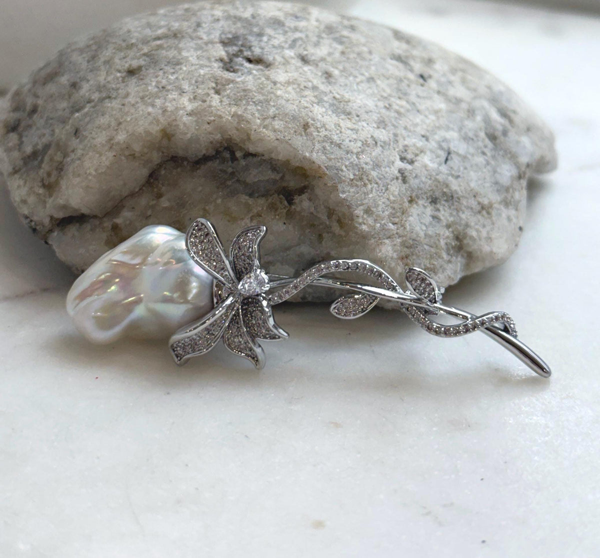 Elegant white pearl brooch with delicate vine details and sparkling crystal accents.